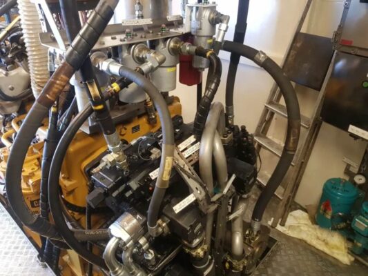 Na zdjęciu widoczny jest złożony układ hydrauliczny zamontowany prawdopodobnie w maszynowni statku lub na jego pokładzie technicznym.